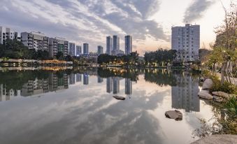 a city skyline reflected in a calm lake , with tall buildings and trees visible at the end at Atour Hotel
