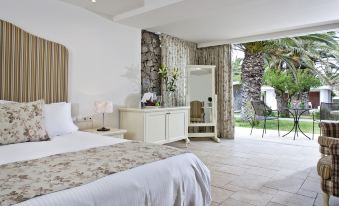 a large bedroom with a white bed , dresser , and sliding glass door leading to an outdoor patio at Civitel Creta Beach