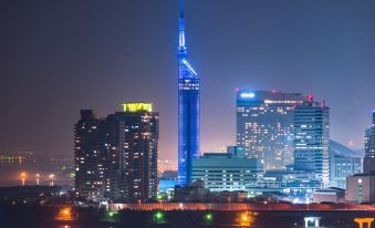 a city skyline at night , with a tall blue skyscraper illuminated against the dark sky at Hotel Monte Hermana Fukuoka