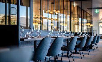 a long dining table with multiple chairs and wine glasses , set in a modern restaurant at Mercure Geneva Airport