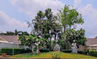 a lush green park with tall trees , statues , and flowers , providing a serene and natural environment at OYO 926 Sydney Resort
