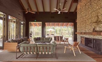 a cozy living room with a couch , chairs , and a tv . the room has a wooden floor , ceiling fans , and windows at Mt Mulligan Lodge