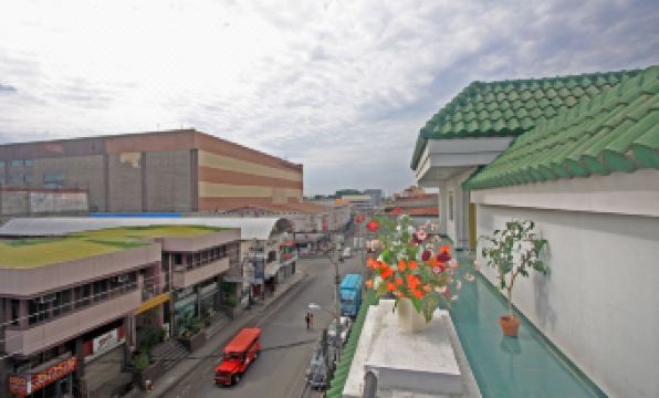 a busy city street with a red truck driving down the road , surrounded by buildings and traffic at Hotel Galleria