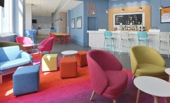 a brightly colored lounge area with colorful chairs , a bar , and a variety of seating options at Travelodge St. Clears Carmarthen