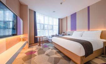 The top floor of the hotel features a spacious bedroom with large windows, a double bed, and a desk in the center at Lavande Hotel (Kunming Xishan Wanda Plaza Railway Station)