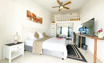 a spacious bedroom with a king - sized bed , a television , and a tv mounted on the wall at The Beachhouse