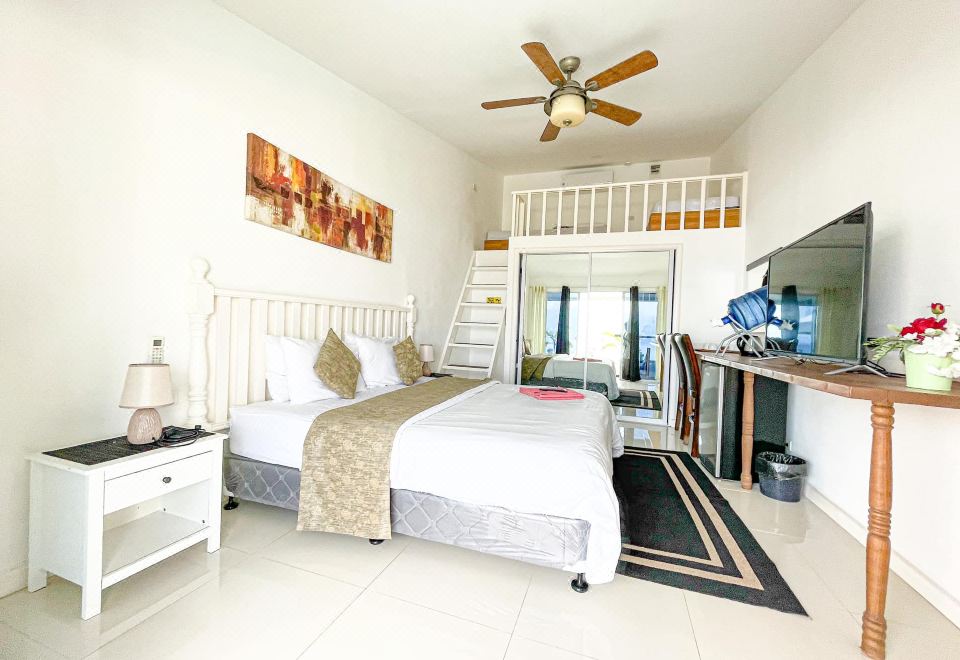 a spacious bedroom with a king - sized bed , a television , and a tv mounted on the wall at The Beachhouse