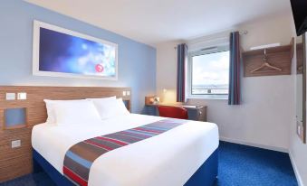 a modern hotel room with blue carpet , white bed , and window , providing ample light and ventilation at Travelodge Porthmadog