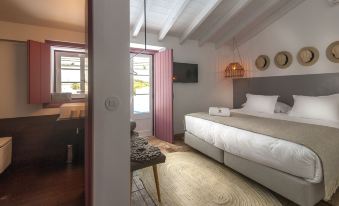 a bedroom with a large bed , a bathroom visible through an open doorway , and a door leading to another room at Herdade Do Touril