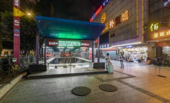 In a city at night, people are walking around and there is an entrance to an underground parking garage at Yimi Hotel (Guangzhou Sanyuanli Subway Station Jinlong Tengfei Fashion City Branch)