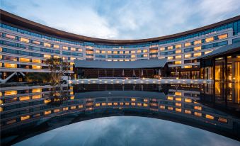 At night, there is a picturesque exterior view featuring a large pool in the foreground and a beautifully lit building in the background at Joyhub Air Hotel