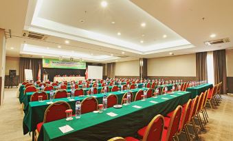 a large conference room with rows of red and green chairs arranged in front of a stage at Metland Hotel Bekasi