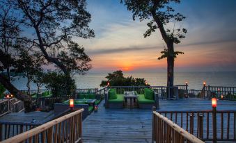 a wooden deck overlooking the ocean , with several chairs and tables set up for outdoor dining at Soneva Kiri