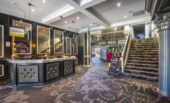 a hotel lobby with a staircase leading to the second floor , a reception desk , and several chairs at Nightcap at Skyways Hotel