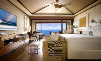 a modern living room with large windows offering an ocean view , featuring a white sofa and wooden flooring at Four Seasons Resort Lana'i