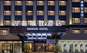 The front entrance of a hotel is shown in a time-lapse video at night, featuring an illuminated sign above it at Manxin Hotel