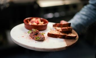 a dining table with a plate of food on it , including meat and bread , as well as a bowl of sauce at Karriview