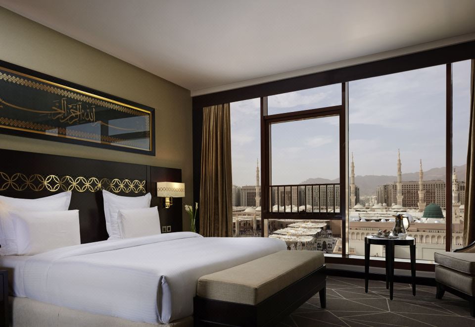 a hotel room with a large bed , a couch , and a window overlooking a city at Pullman Zamzam Madinah