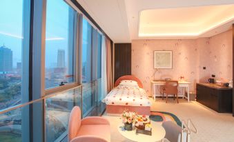 The bedroom features large windows and a balcony that overlooks the city, with an elegant bed positioned in front at Yindu Hotel