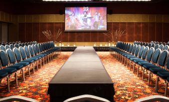 a large room with a long table and rows of chairs , and a screen on the wall at Maestral Resort & Casino