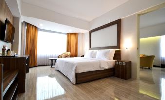 a large bed with white linens is in a room with wooden floors and a window at Horison Ultima Bandung