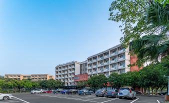 A large apartment building stands in the background of an empty street with parked cars at Ausotel Smart Guangzhou Baiyun International Airport Terminal 1