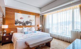 The bedroom features large windows and double beds with oriental style bedspreads at New Joyful Hotel