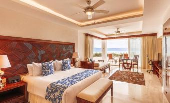 There is a bedroom with a large bed and a balcony that overlooks the pool area at Ionian Blue Bungalows and Spa Resort