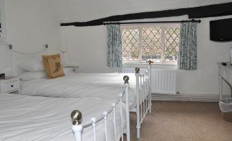 a white bedroom with two beds , one on the left side of the room and the other on the right side at The Brocket Arms