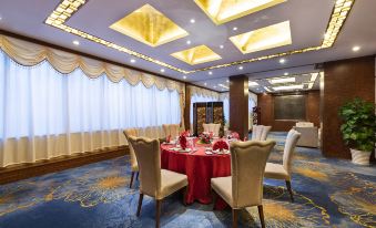 A room is furnished with tables and chairs, and there is an ornate wallpaper on one side at Novotel Beijing Peace