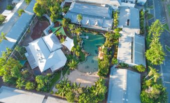 aerial view of a residential area with houses and a pool , surrounded by trees and palm trees at Cairns Colonial Club Resort