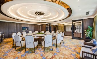 A spacious event space is arranged with tables and chairs in the center at Hainan Grand Hotel