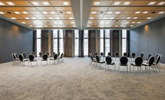 a large conference room with rows of chairs arranged in a semicircle , and a podium at the front of the room at HYPERION Hotel Leipzig