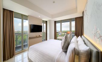 a large bedroom with a king - sized bed , a flat - screen tv mounted on the wall , and a sliding glass door leading to a at Oakwood Apartments Pik Jakarta