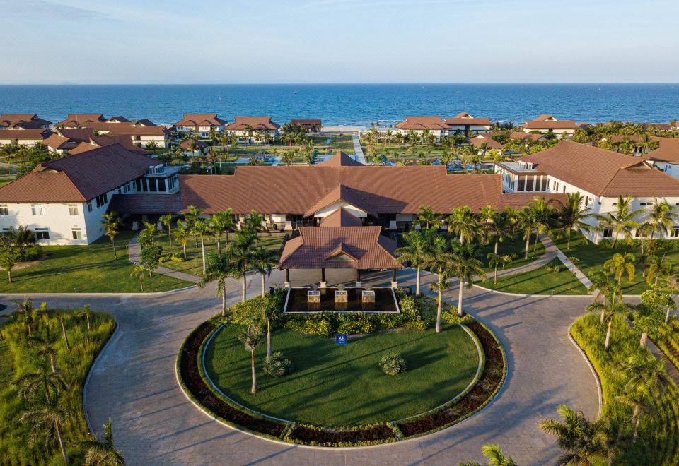 a resort with a large pool surrounded by multiple buildings , including a hotel , a restaurant , and a conference center at Tui Blue Nam Hoi An