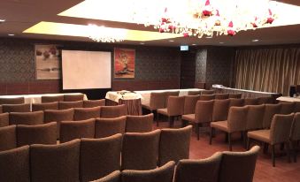 The venue for an event or conference is a spacious auditorium with rows of tables and multiple screens at the front at Ramada Hong Kong Grand
