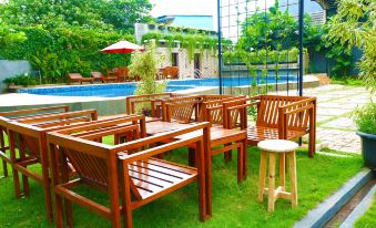 a wooden dining table and chairs set up in a grassy area near a pool at Metland Hotel Bekasi