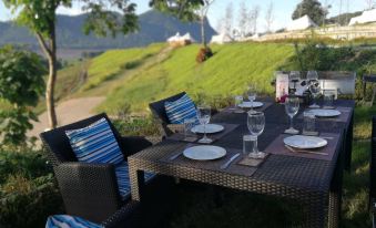 an outdoor dining area with a table set for a meal , surrounded by a lush green lawn at Chiangkhan River Green Hill