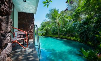 a swimming pool surrounded by palm trees and lush greenery , with a staircase leading down to the water at Merusaka Nusa Dua