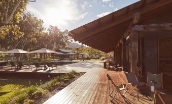 a wooden deck with umbrellas and chairs , surrounded by trees and a body of water at Mt Mulligan Lodge