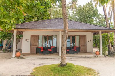 a small , tropical beach house with two doors and a tree in front of it at Vilamendhoo Island Resort & Spa