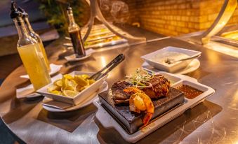 a dining table with a variety of food items , including steak , shrimp , and other dishes at Carnarvon Motel