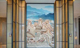 In an Asian-style room, there is a large mural on the wall along with other pieces of art at Shantou Marriott Hotel
