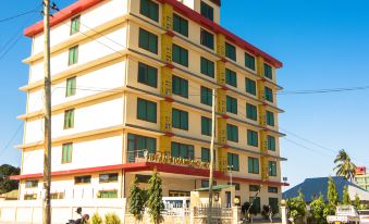 "a tall building with yellow and red accents is surrounded by a sign that says "" hotel ""." at Tiffany Diamond Hotels - Mtwara