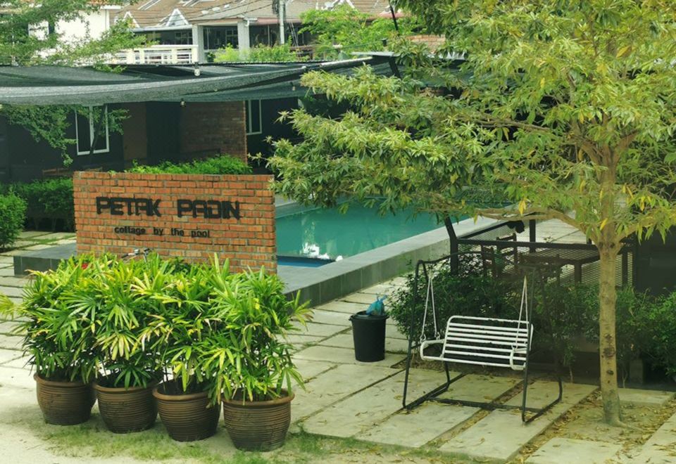"a brick building with a sign that reads "" petr papon "" is surrounded by potted plants and a bench" at Petak Padin Cottage by The Pool