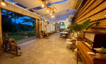 a large , open living space with a dining table and chairs , as well as several chairs arranged around them at Proud Phu Fah Hip & Green Resort