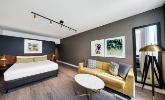 a modern bedroom with a yellow bed , a couch , and a dining table in the room at Vibe Hotel Sydney