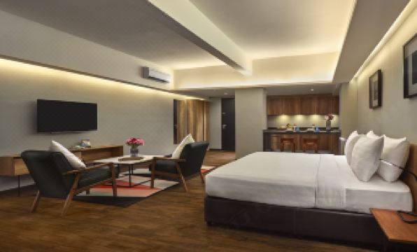 a modern hotel room with a large bed , dining table , and a kitchenette , all decorated in warm colors at Tropics Eight Suites