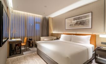 a large , neatly made bed is the focal point of a modern hotel room with a comfortable seating area at Artels