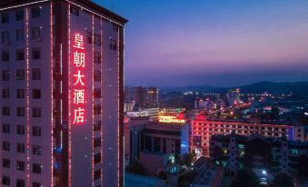 a city skyline at night , with a tall building illuminated by red lights and a sign in chinese at Dynasty Hotel